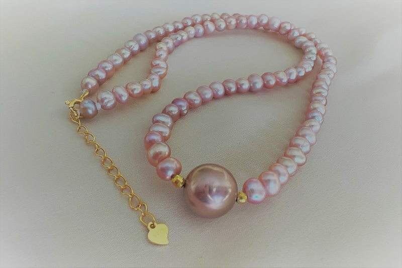 A string of pearls with a larger lavender pearl gold vermeil chain in the center displayed on a white background.