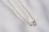 A string of pearls with a larger white pearl in the center displayed on a white background
