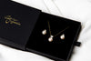 Pearl earrings and matching necklace in a black gift box on a white background