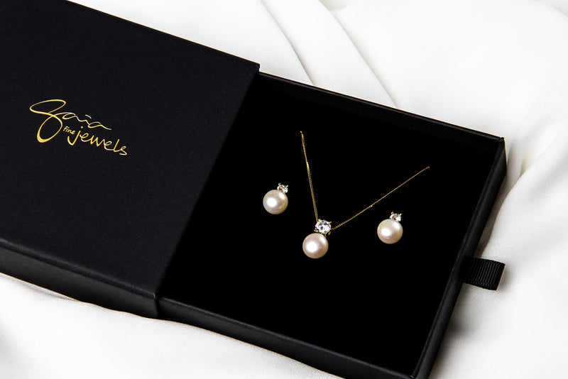 Pearl earrings and matching necklace in a black gift box on a white background