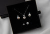 Pearl earrings and matching necklace in a black gift box on a white background