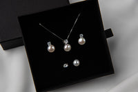 Pearl earrings and matching necklace in a black gift box on a white background