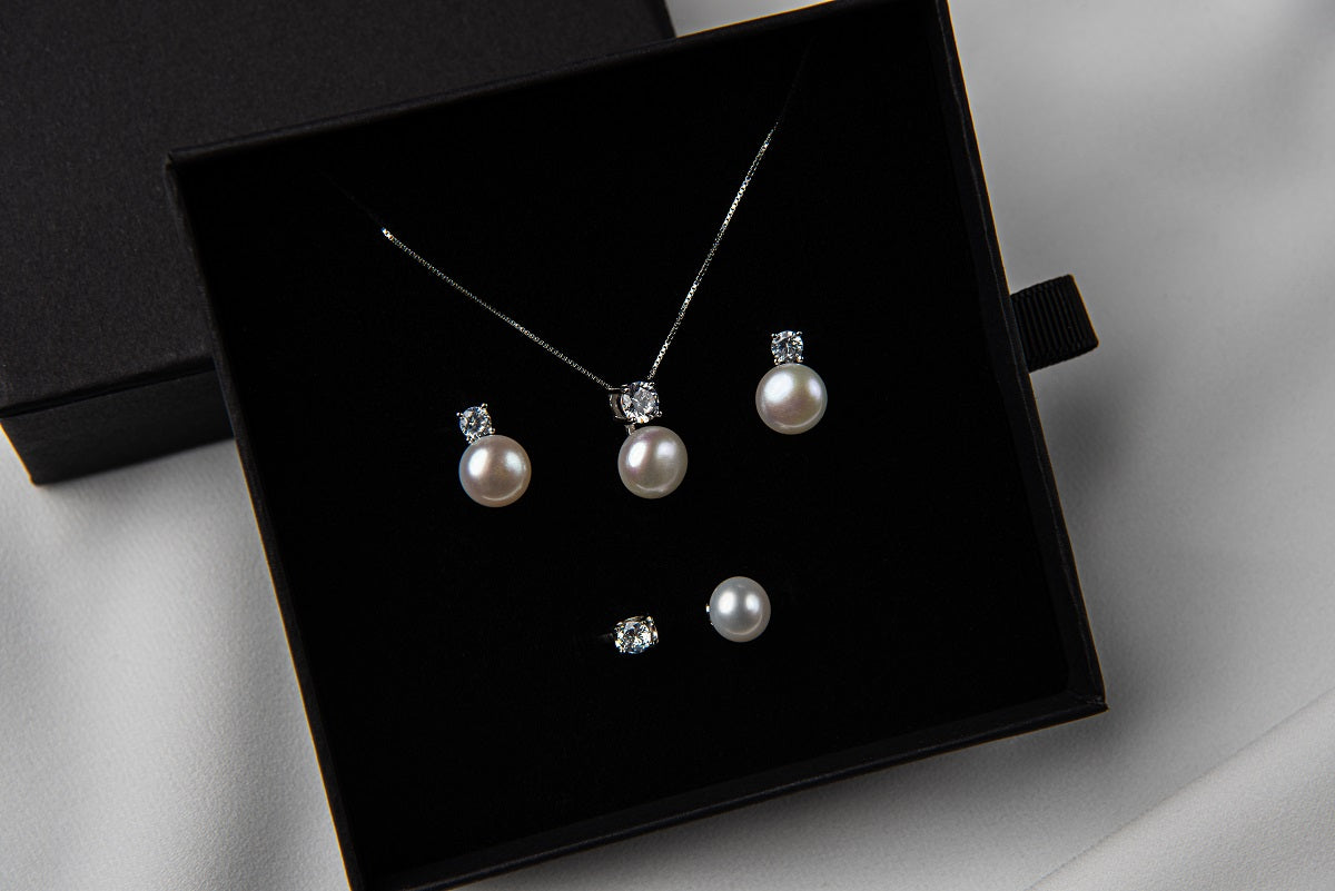 Pearl earrings and matching necklace in a black gift box on a white background