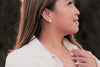 Asian woman wearing a pearl neckalce and earring set with a blurred background