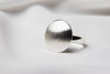 A sterling silver ring with a matte dome top and polished band, displayed on a white fabric surface.