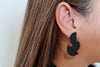 close up of a woman wearing matt black eaerring shaped in 3 overlapping half circles