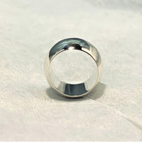 The Classic Band Ring in polished silver on a fabric background