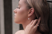 A woman wearing a pearl earrling on a gold vermeil hook