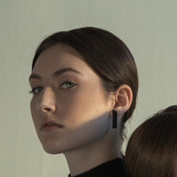 Close up of a model wearing a minimalist design matt black earring