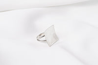 A polished silver ring with a concave design, displayed on a white surface.