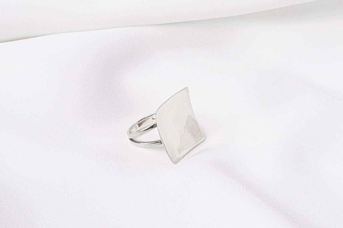 A polished silver ring with a concave design, displayed on a white surface.