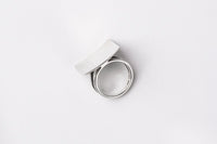 A polished silver ring with a concave design, displayed on a white surface.