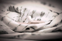 A polished silver ring with a concave design, displayed on a textured surface