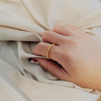 A close up of a models have wearing a gold textured ring