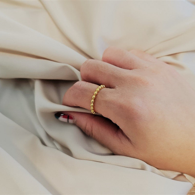 A close up of a models have wearing a gold textured ring