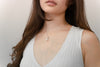 A women wearing a sterling silver necklace with a white freshwater pearl and a small diamond cubic zirconia,.