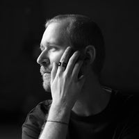 Black and white picture of a close up of a man wearing a ring holdng his hand close to his face
