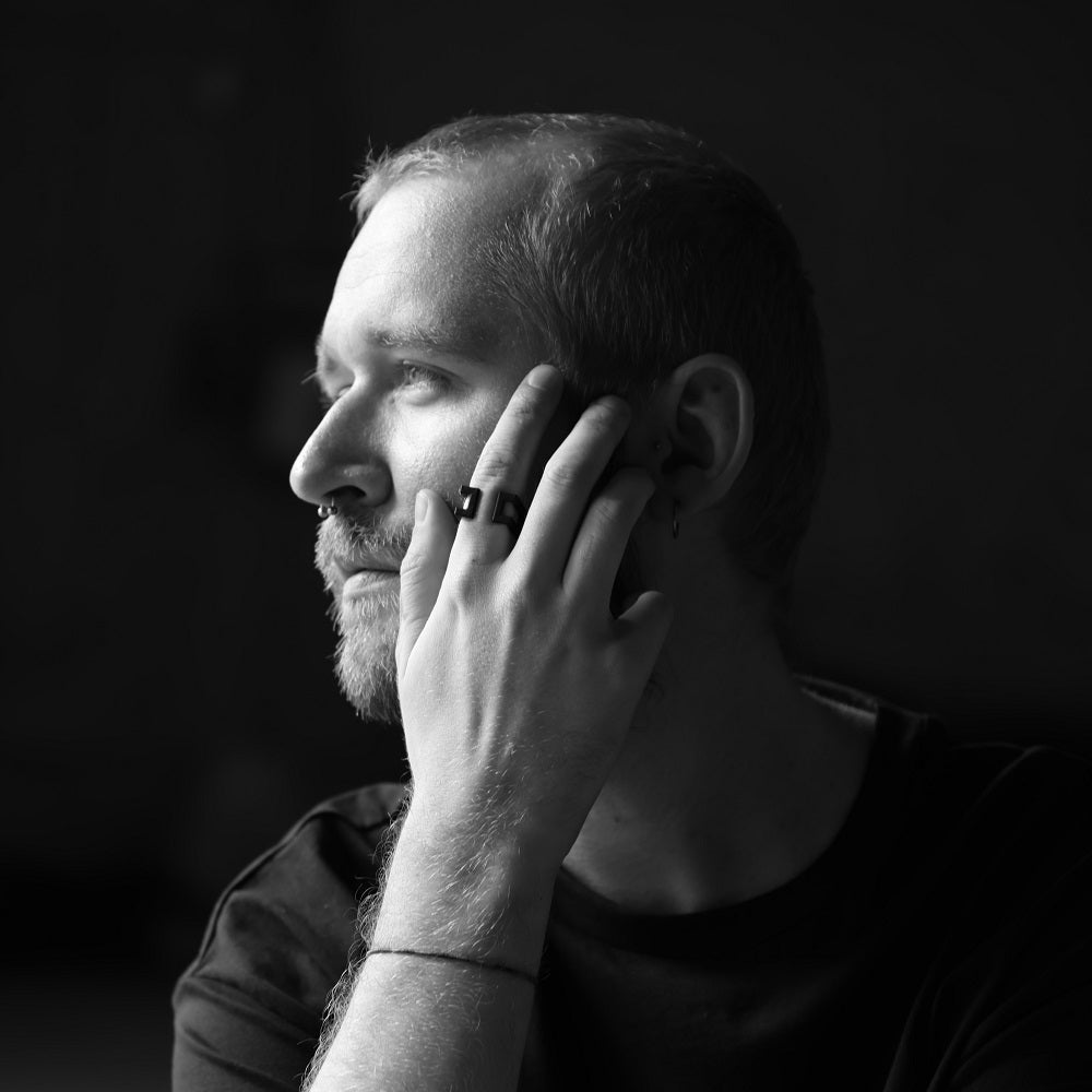 Black and white picture of a close up of a man wearing a ring holdng his hand close to his face