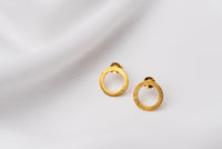 A pair of matte gold stud earrings with a butterfly back design, displayed against a white fabric background.
