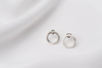 A pair of matte silver stud earrings with a butterfly back design, displayed against a white fabric background.