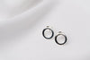 A pair of silver stud earrings with a butterfly back design, displayed against a white fabric background.