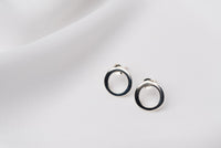 A pair of silver stud earrings with a butterfly back design, displayed against a white fabric background.