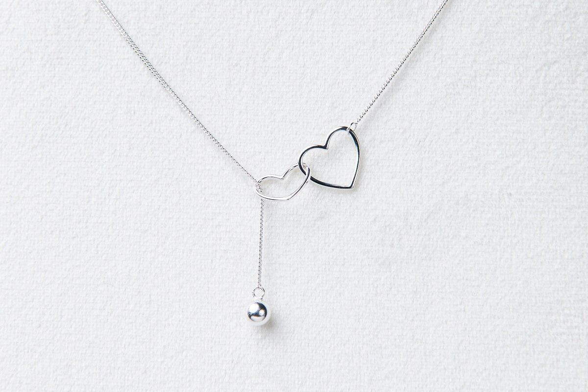 A sterling silver necklace with a double layer design featuring heart-shaped pendants.