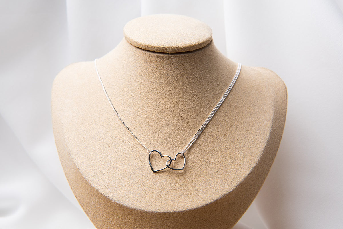 A sterling silver necklace with a double layer design featuring heart-shaped pendants.
