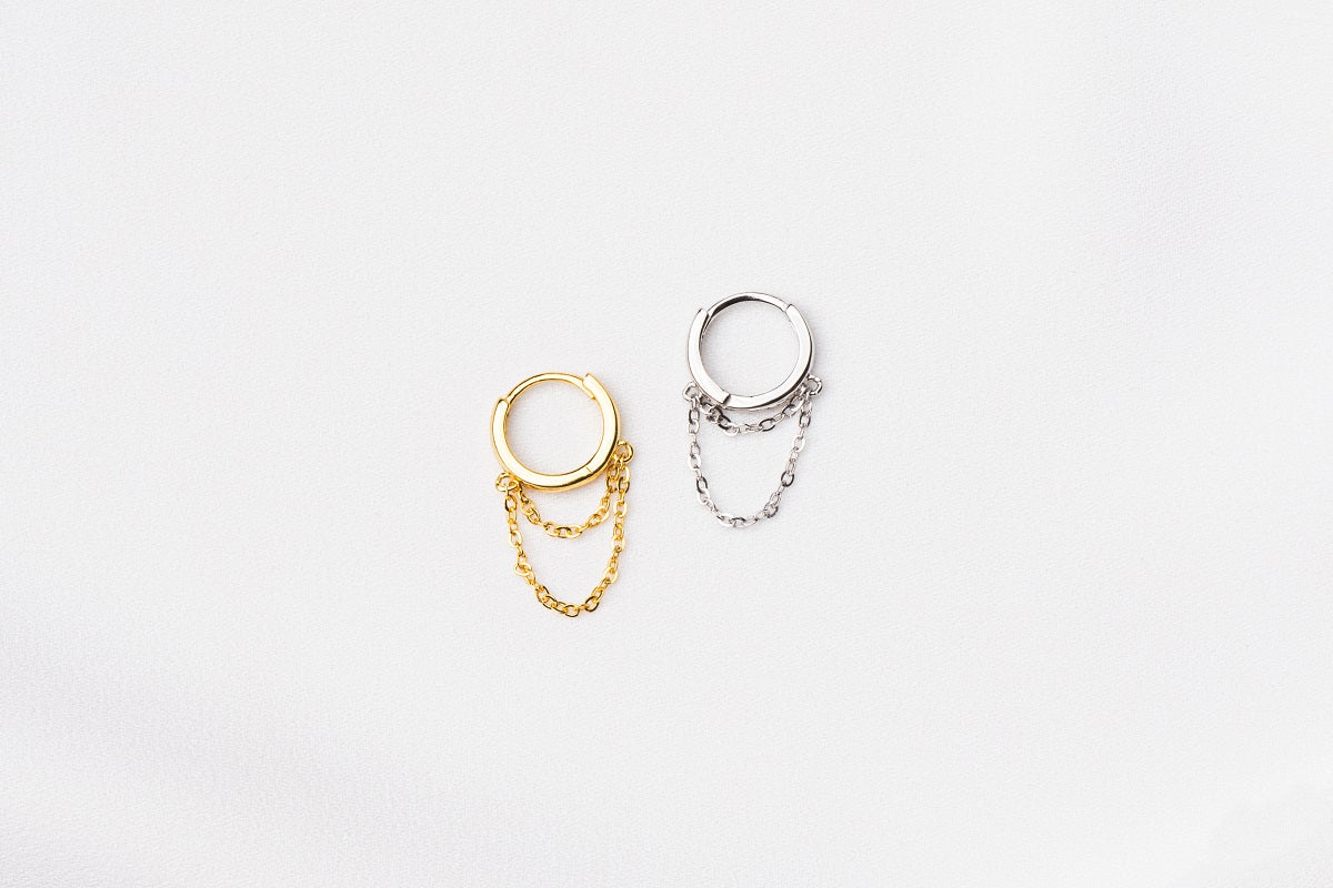 Two huggie earrings, one with a gold vermeil chain and the other with a silver chain, set against a white background.