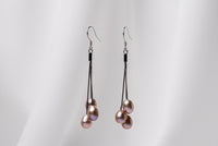 A pair of black drop earrings with 3 pearls on a white background