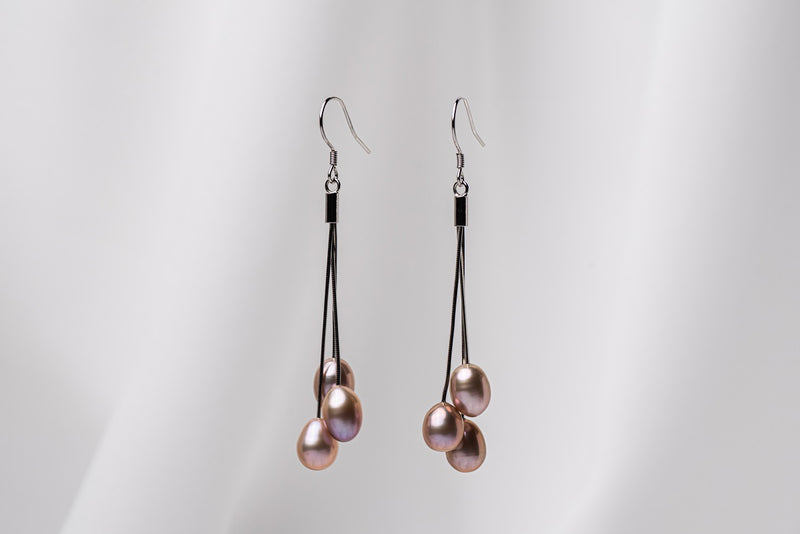 A pair of black drop earrings with 3 pearls on a white background