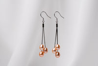 a pair of black drop earrings with 3 pearls on a white background