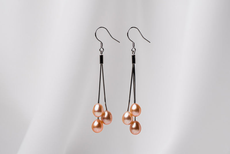 a pair of black drop earrings with 3 pearls on a white background
