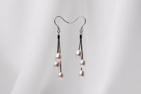 a pair of black drop earrings with 3 pearls on a white background