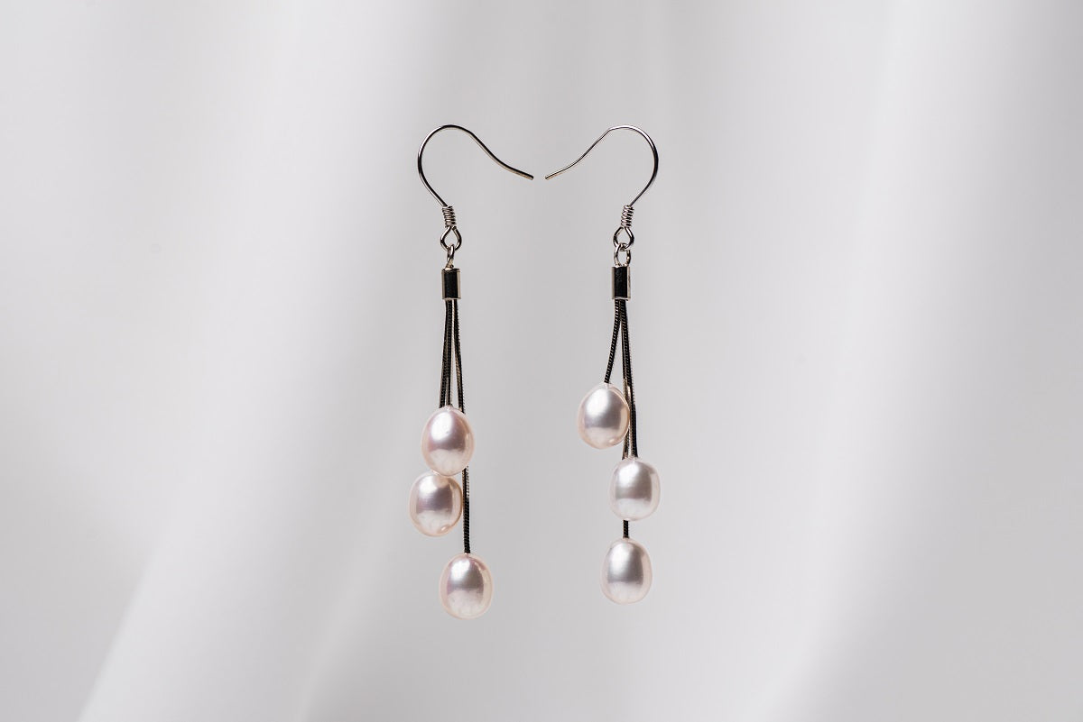 a pair of black drop earrings with 3 pearls on a white background