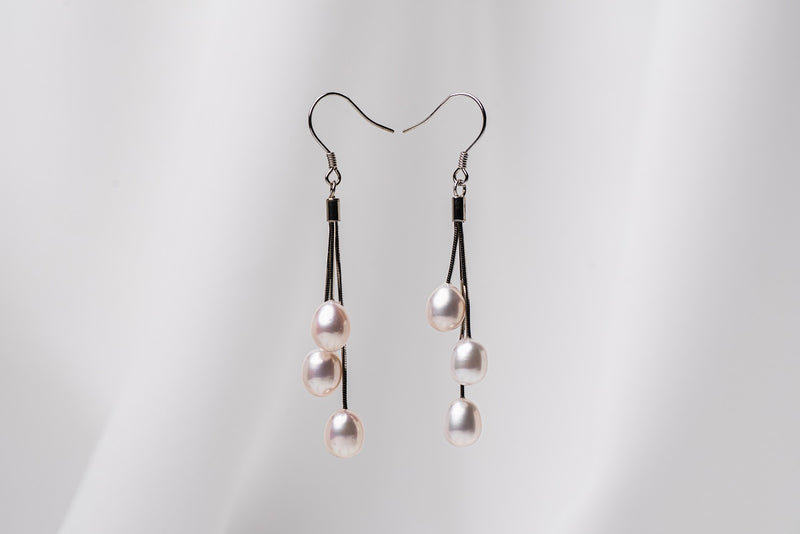 a pair of black drop earrings with 3 pearls on a white background