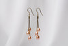 a pair of gold drop earrings with 3 pearls on a white background