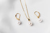 A set of jewelry including a necklace and earrings with white drop-shaped pearls, sterling silver and gold vermeil accents on a white background.