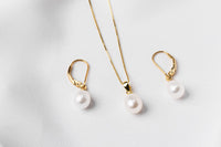 A set of jewelry including a necklace and earrings with white drop-shaped pearls, sterling silver and gold vermeil accents on a white background.