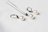 A set of jewelry including a necklace and earrings with white drop-shaped pearls, sterling silver on a white background.