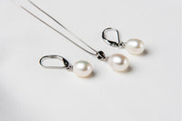 A set of jewelry including a necklace and earrings with white drop-shaped pearls, sterling silver on a white background.