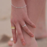 A womans hand wearing a silver ring woth the word "FEARLESS" inscribed on the band.