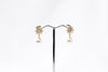 A pair of pearl earrings with butterfly backs and dangle design, featuring white pearls and a sparkling floral-shaped pendant in gold vermeil and diamond cubic zirconia.