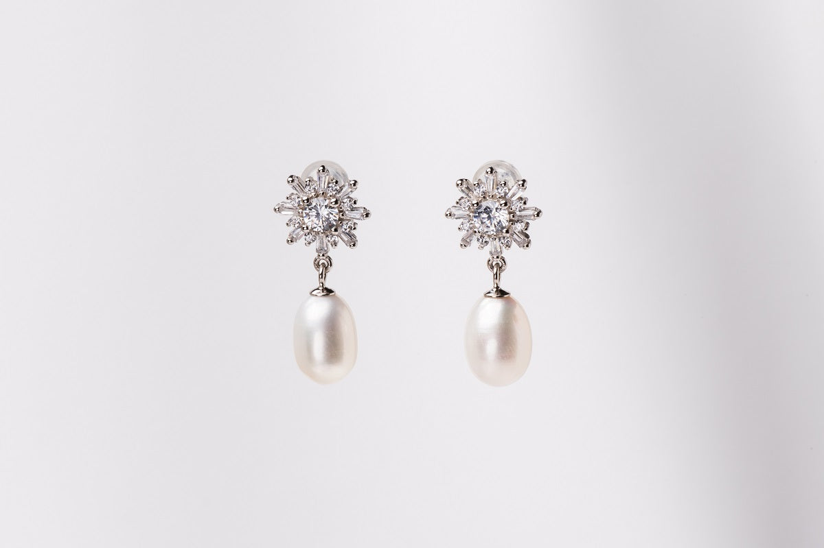 A pair of pearl earrings with butterfly backs and dangle design, featuring white pearls and a sparkling floral-shaped pendant and diamond cubic zirconia.