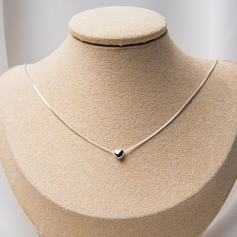 A silver chain necklace with a small heart pendant.
