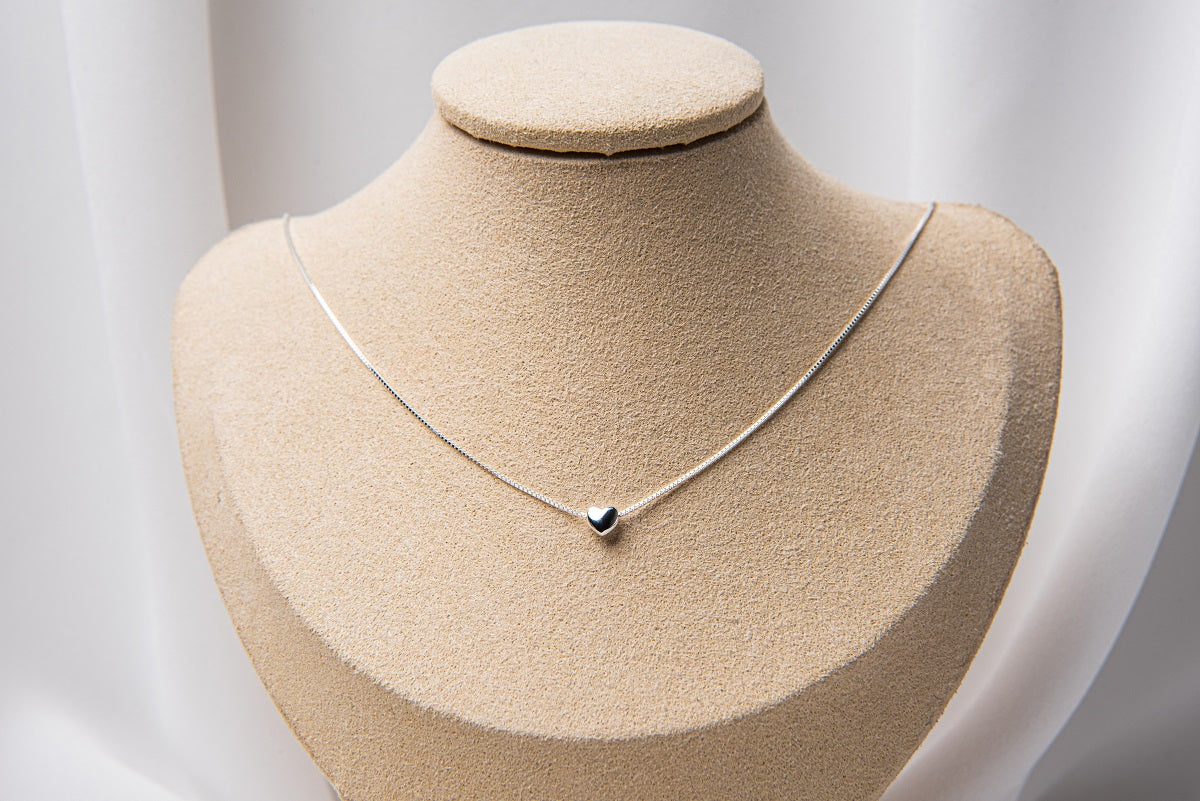 A silver chain necklace with a small heart pendant.