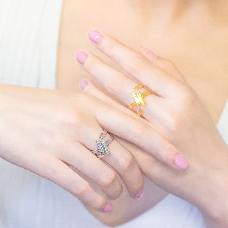 A close up of a model wearing a gold and a silver ring shaped like a hash-tag