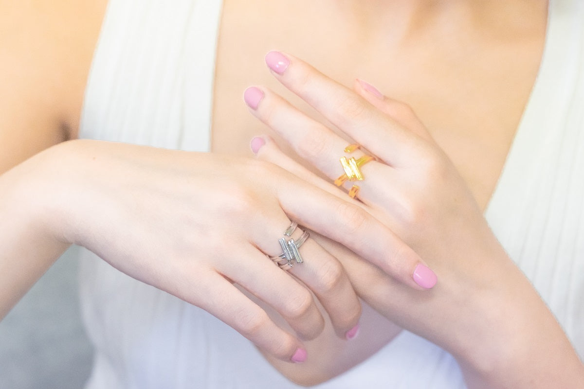 A close up of a model wearing a gold and a silver ring shaped like a hash-tag