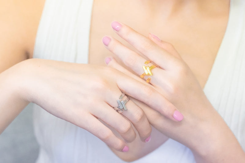 A close up of a model wearing a gold and a silver ring shaped like a hash-tag