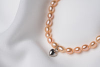 A sterling silver and gold vermeil champagne pearl necklace with a potato-shaped pearl drop and a silver heart-shaped clasp, displayed on a white fabric surface.